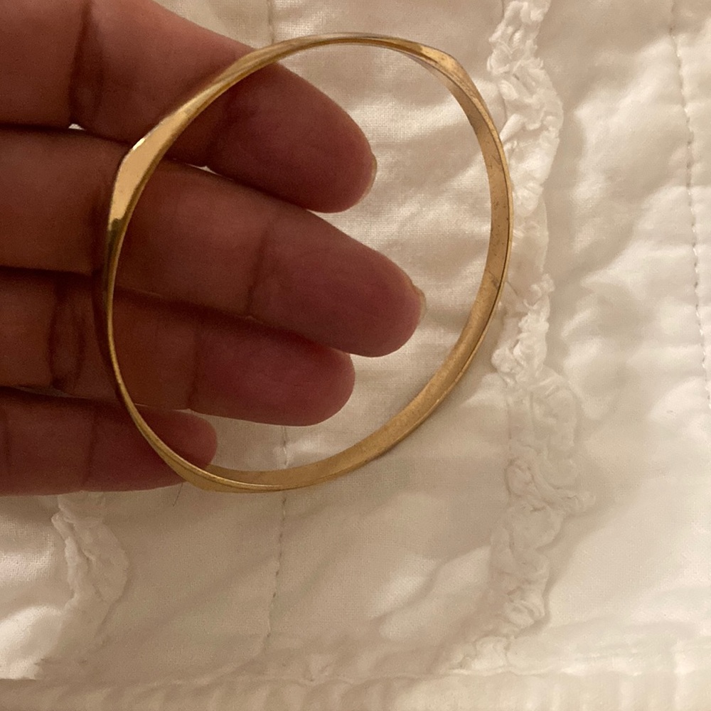 Shiny gold tone vintage bangle with angles on all sides.